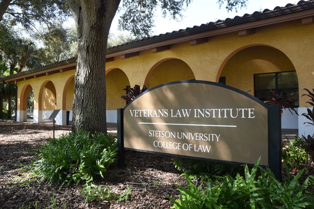A one-story, Mediterranean revival-inspired building, in front of which is a large sign that says "Veterans Law Institute, Stetson University College of Law."