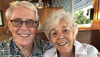 An elderly couple smiles for a close-up shot.