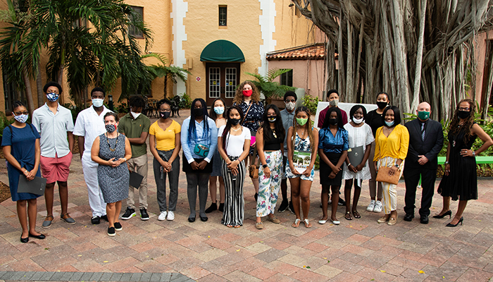 A group of about 20 students and professors poses in Stetson Law's Banyan Courtyard