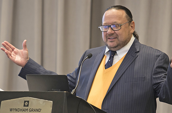 Professor Peter Lake speaks at a podium at the higher education conference