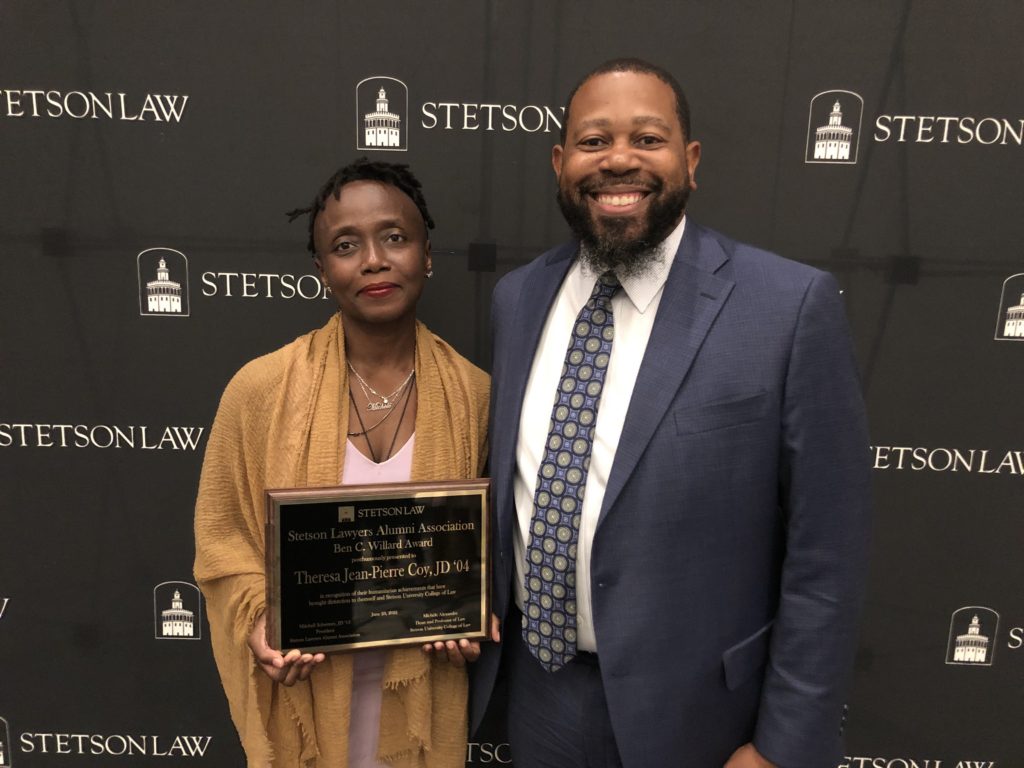 Dean Michele Alexandre poses with alumnus Travis Coy before handing him a plaque.