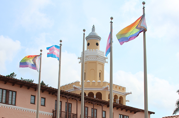 Four LGBTQ Pride flags fly in front of the tower at Stetson Law.