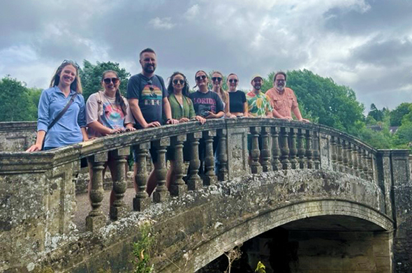 A group of students stands along a stone bridge in Oxford, England