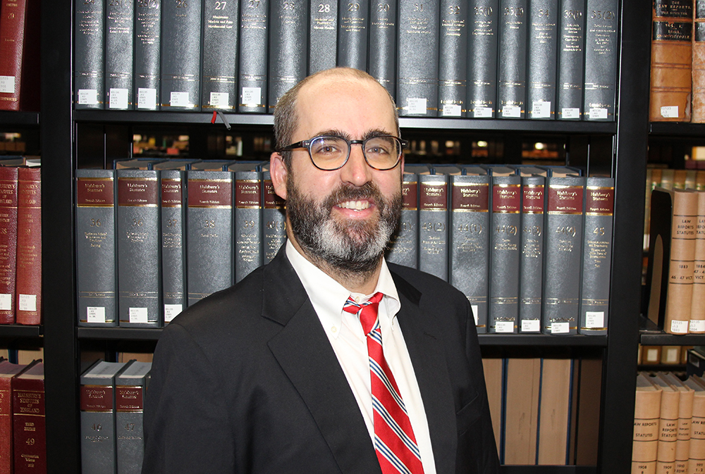 Law Professor William Bunting stands in front of a stack of law books