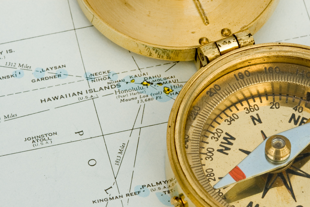 An antique compass on top of a map of Hawaii