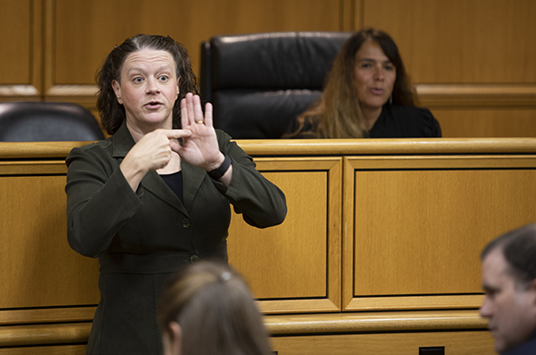 A sign language interpreter practices signing in a courtroom setting