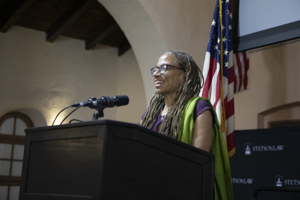 A woman speaks from a podium in the Great Hall.