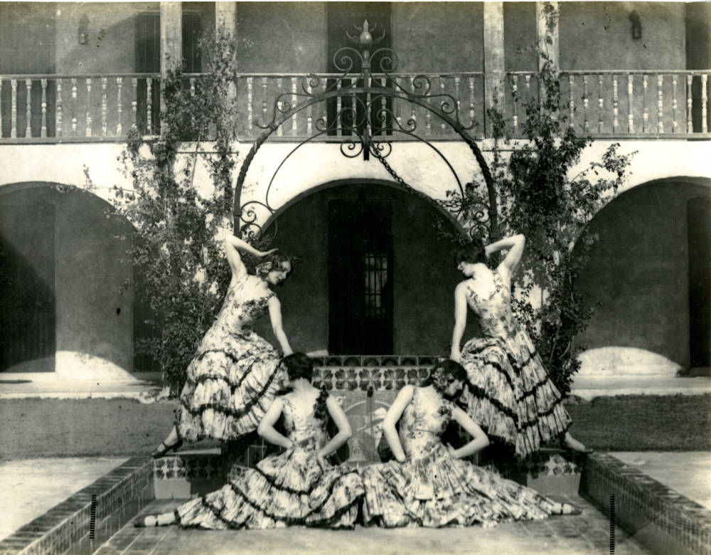 A black-and-white image featuring four ornately dressed women posing on Stetson Law's "Wishing Well" fountain.