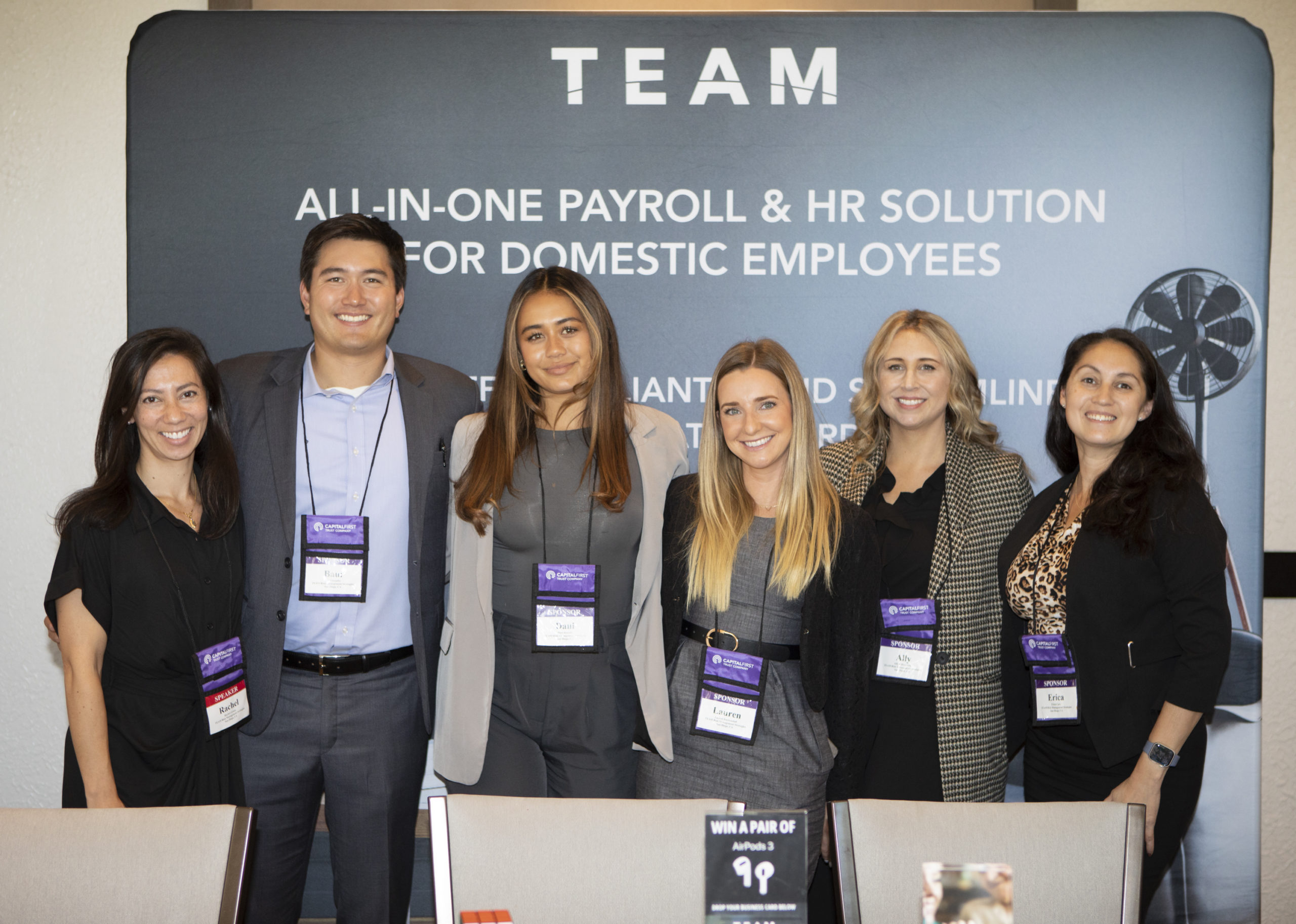 Six young professionals pose for a photo in front of a banner that reads "T E A M - All-in-one payroll & HR solutions for domestic employees."