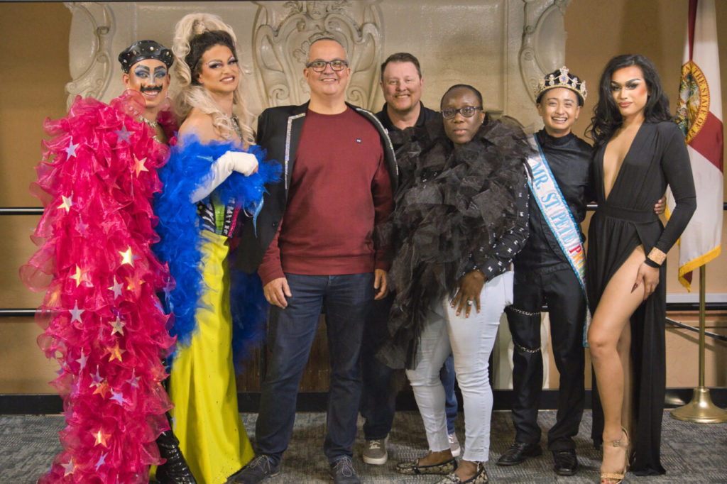 Drag performers and campus officials pose in front of the marble fireplace in Stetson's Great Hall.