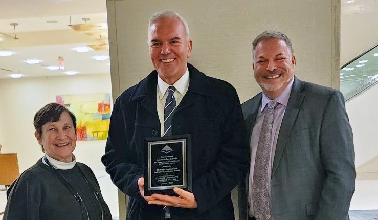 Two professors and one administrator show off an award from the Association of American Law Schools