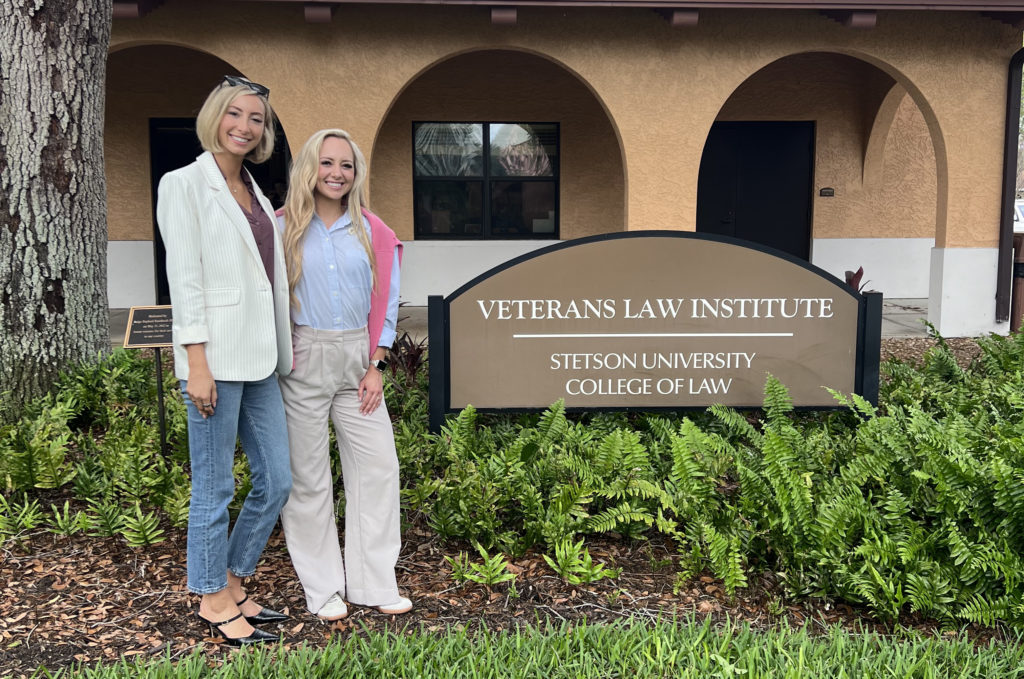 Two women stand in front of a building with a sign that says "Veterans Law Institute Stetson University College of Law."