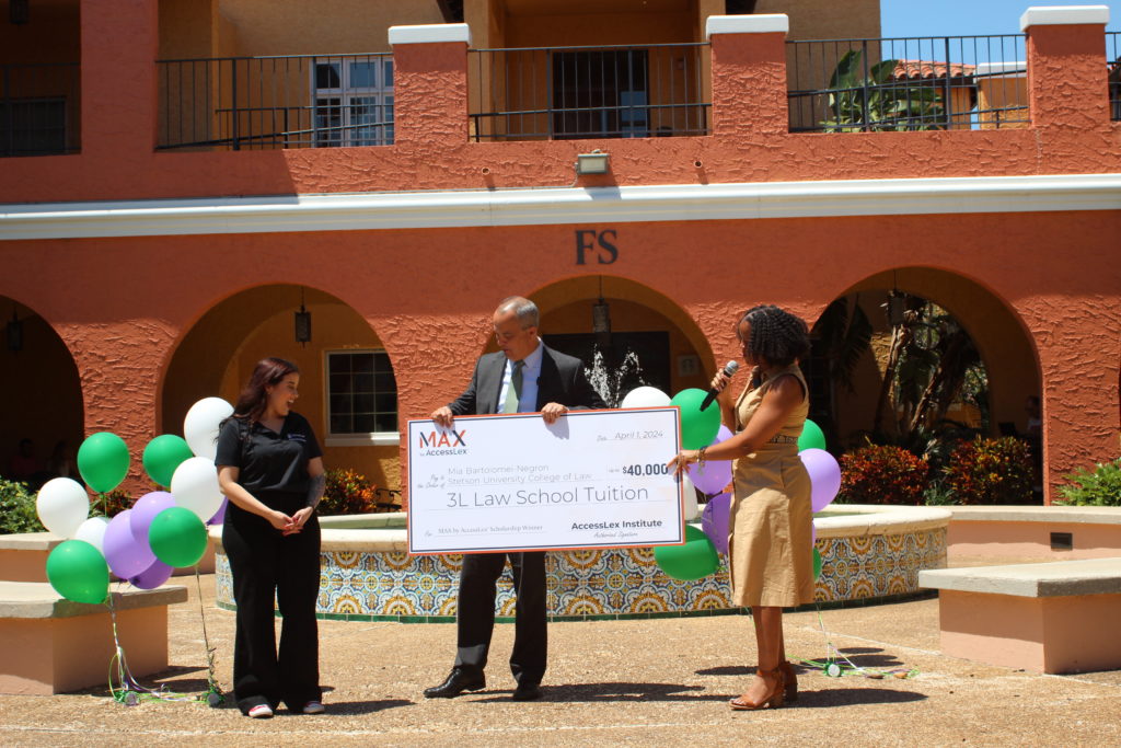 A female law student is presented with an oversized check representing a $40,000 scholarship.