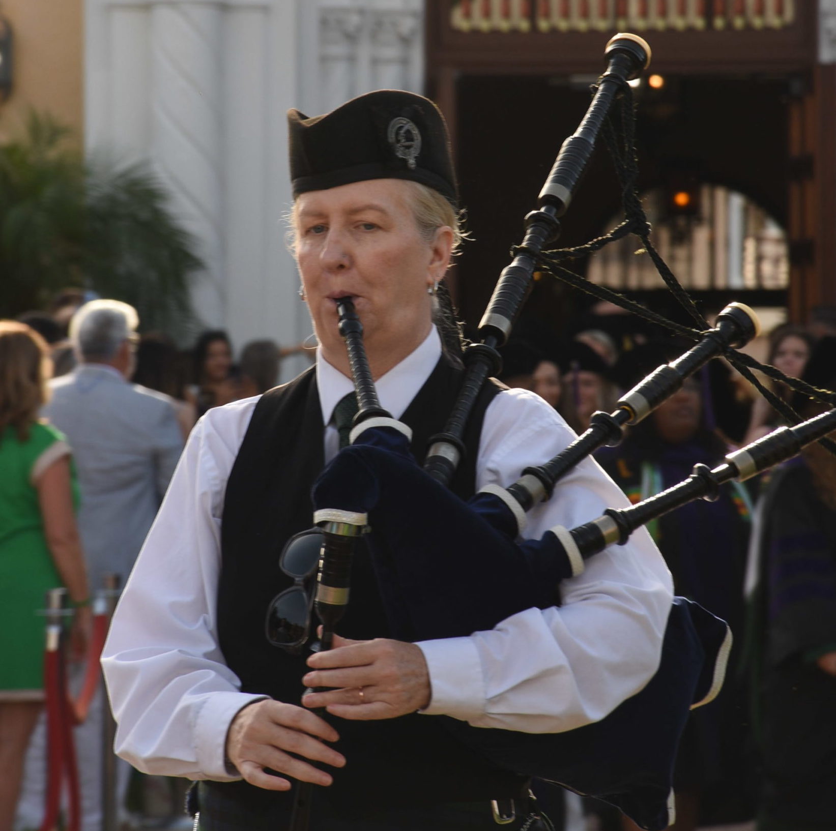 A woman plays a bagpipe as she walks.