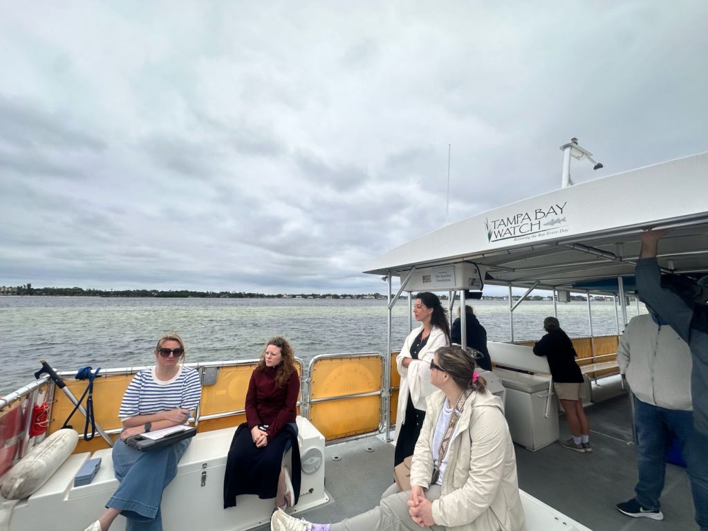 A group of women sit on a boat overlooking the calm waters of Tampa Bay.