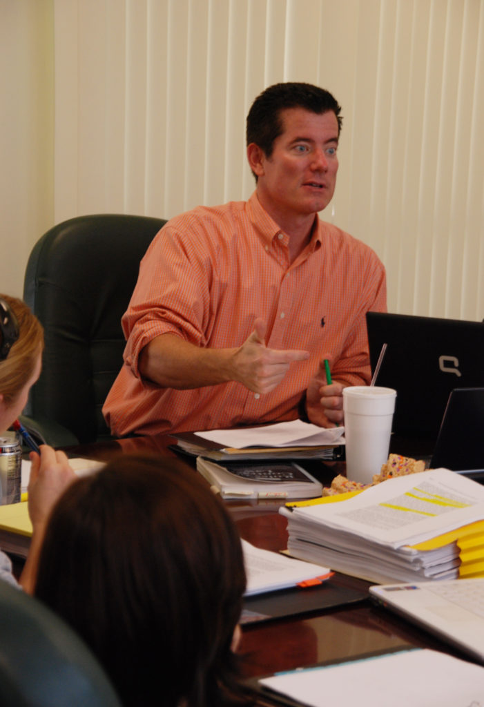 Law Professor Joseph Morrissey wears a salmon-colored shirt and sits at a seminar table.
