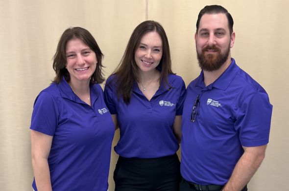 Three young alumni stand with purple shirts promoting Stetson's Veterans Law Institute.