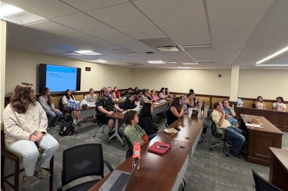 A group of roughly 30 students watch a lecture in a classroom.