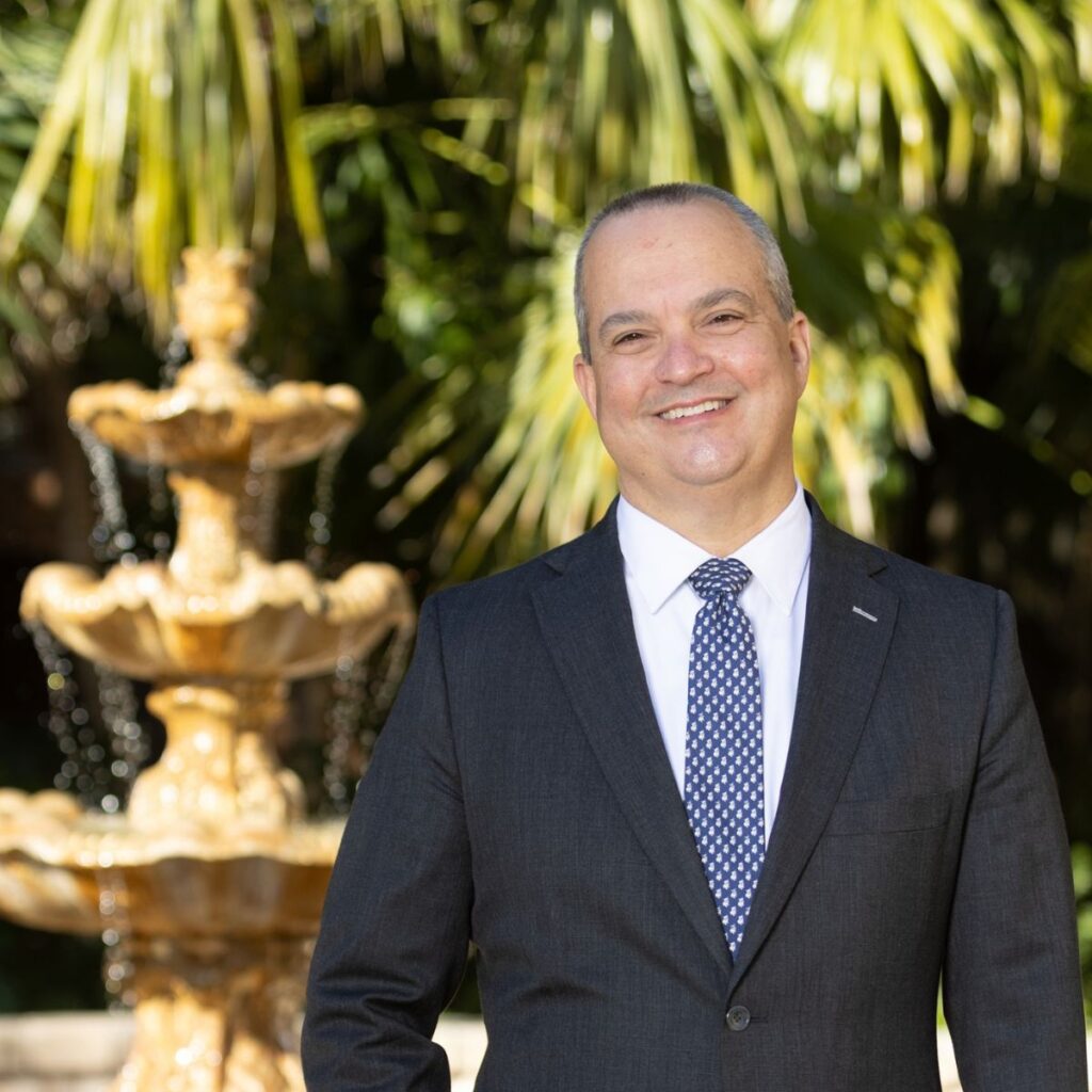 A photo of Dean D. Benjamin Barros standing in front of a fountain on the Stetson Law campus.