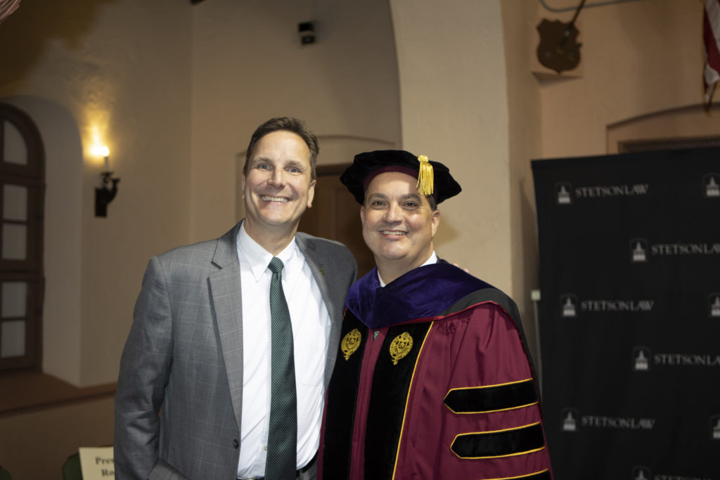 A man in a suit and a man in graduation regalia.