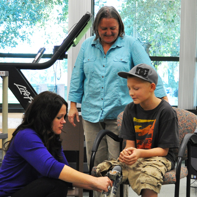 IHSC alum Rachel Friddle and Prof. Michele Skelton help child for prosthetic leg.