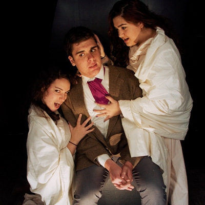 Harker is seduced by vixens while locked in Dracula's castle in "Dracula," presented at Stetson University’s 'Second Stage' in the Museum of Florida Art, 600 N. Woodland Blvd., DeLand. Left to right: Olivia Moeschet, Alex Schelb, Roxy Ghamgosarnia. Photo by Ken McCoy.