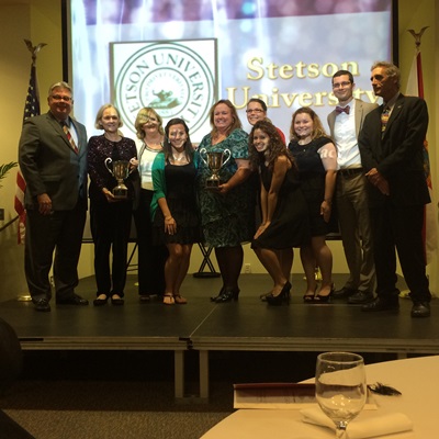 FLCC top award -Left to right: Jim Murdaugh (President of Tallahassee Community College), Bette Heins, Kathy Piechura-Couture, Heather Hamilton, Karen Beattie (Volusia County Schools - Professional Development Coordinator), Savannah-Jane Griffin (in back), Gladys Valle 14’, Amber Finnicum-Simmons 16’, Kevin Winchell, and Doug MacIsaac (Visiting Assistant Professor; PDS Liaison).