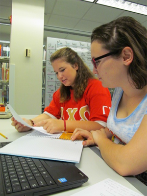 Senior chemistry major and lead tutor, Tracy-Lynn Cleary, in red shirt, works with first year biology major Breanna McDermott. 