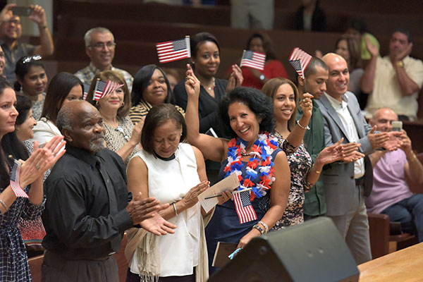 New U.S. citizens applaud and wave the flag after taking the oath of citizenship at Stetson University