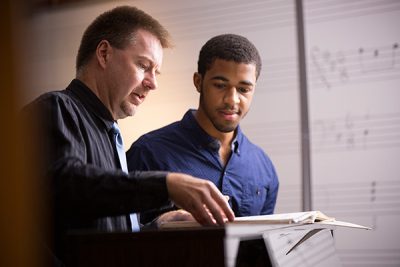 Professor Noel Painter, Ph.D., works with a student in a music class.