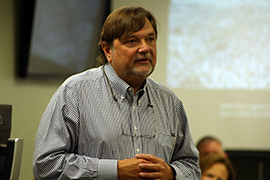 Clay Henderson stands in a meeting, listening
