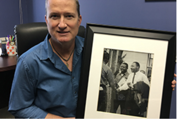 professor holds framed 1963 photo of MLK