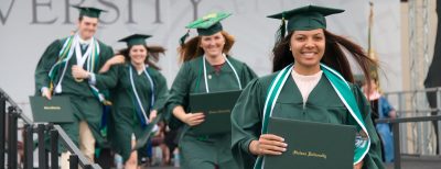 Graduates head off the stage with their new diplomas, all smiles in their caps and gowns.