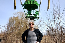 Michael Denner standing under old amusement ride.