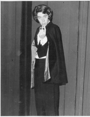A young Allen Enlow in a cape and dark clothing on stage