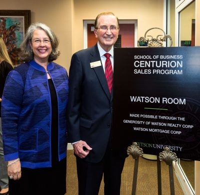 Wendy LIbby and Bill Watson stand by sign for Watson Sales Lab at grand opening