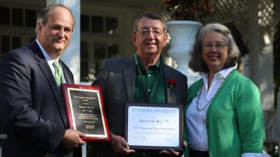 The three pose side by side holding award.