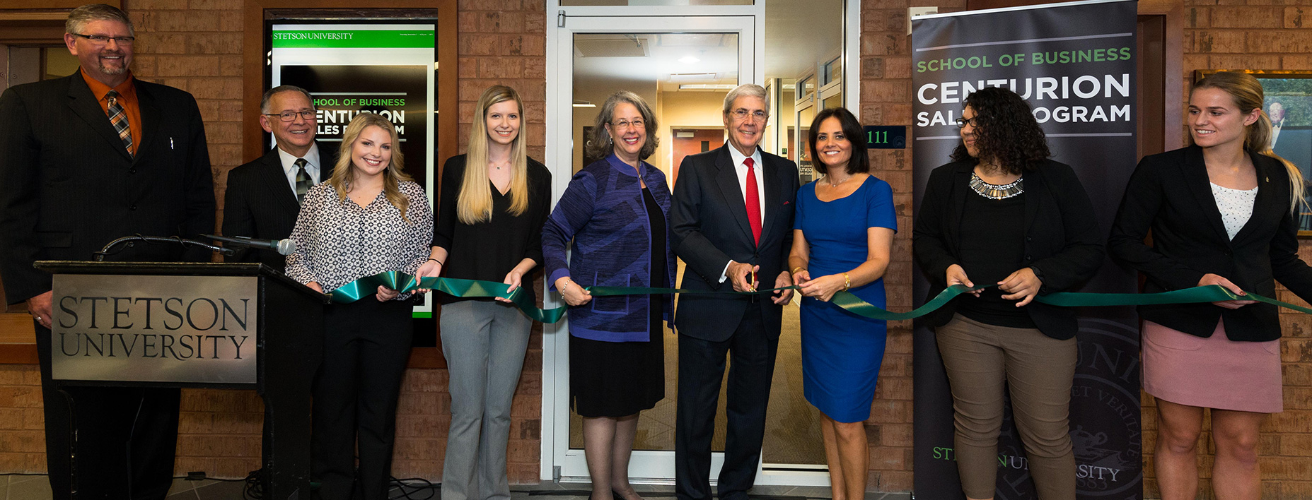 A group of people hold ribbon in front of Sales Center inside the Lynn Business Center