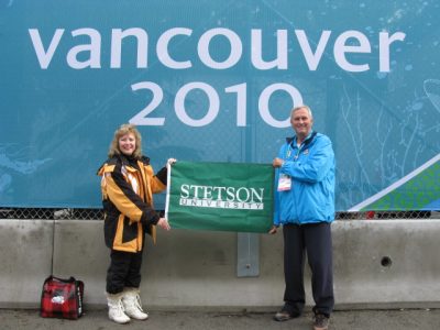 The two stand in winter clothes with a Stetson banner in front of sign that says Vancouver 2010