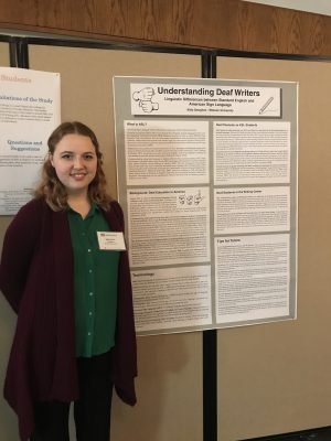 Student stands beside large poster on display at the conference