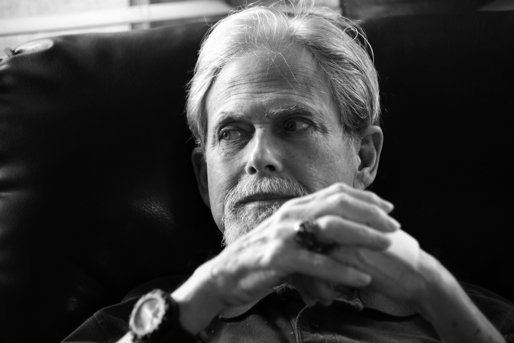 Black and white portrait of Michael Fronk seated in a recliner chair in his home.