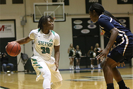 Chambers dribbles the ball down the court during a women's basketball game.