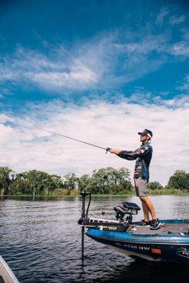 Thomas Oltorik stands fishing on his boat in a river.