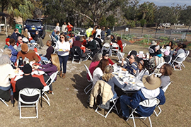 Fold-out tables are filled with diners beside the community garden for the dinner.