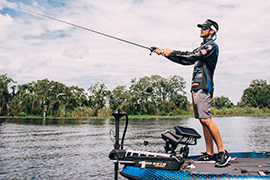 Stetson MBA student Thomas Oltorik stands fishing on his boat in a river