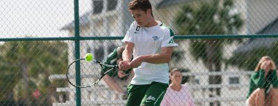 Graham Ball is swinging his tennis racket as the ball approaches him on the court.