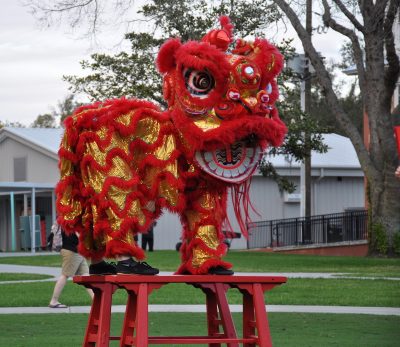 An Asian-themed. bright red and gold dragon costume stands on a wooden platform