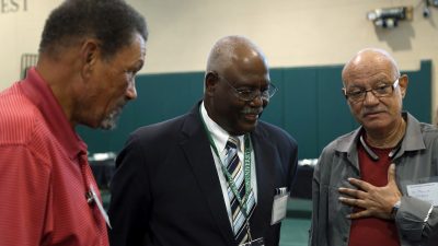 The three man standing talking in the Rinker Field House