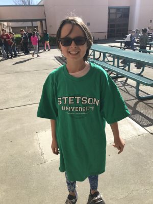 A cute little girl stands in a very large Stetson University green t-shirt.