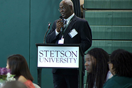 Jim Johnson stands at the podium that says Stetson University with a microphone in hand.